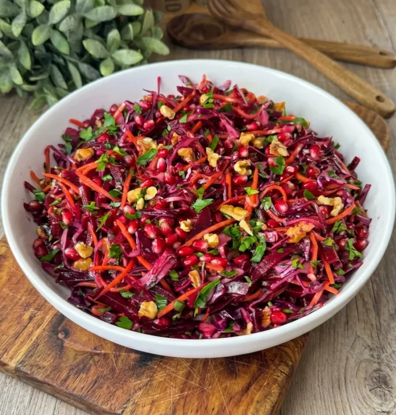 Beet and red cabbage salad with pomegranate seeds and walnuts in a white bowl