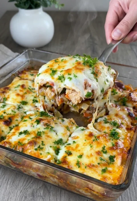 Loaded chicken potato bake with bechamel and melted cheese being served from a glass baking dish